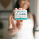 Person holding a skincare product packaging with 'cucumber & aloe vera' text.
