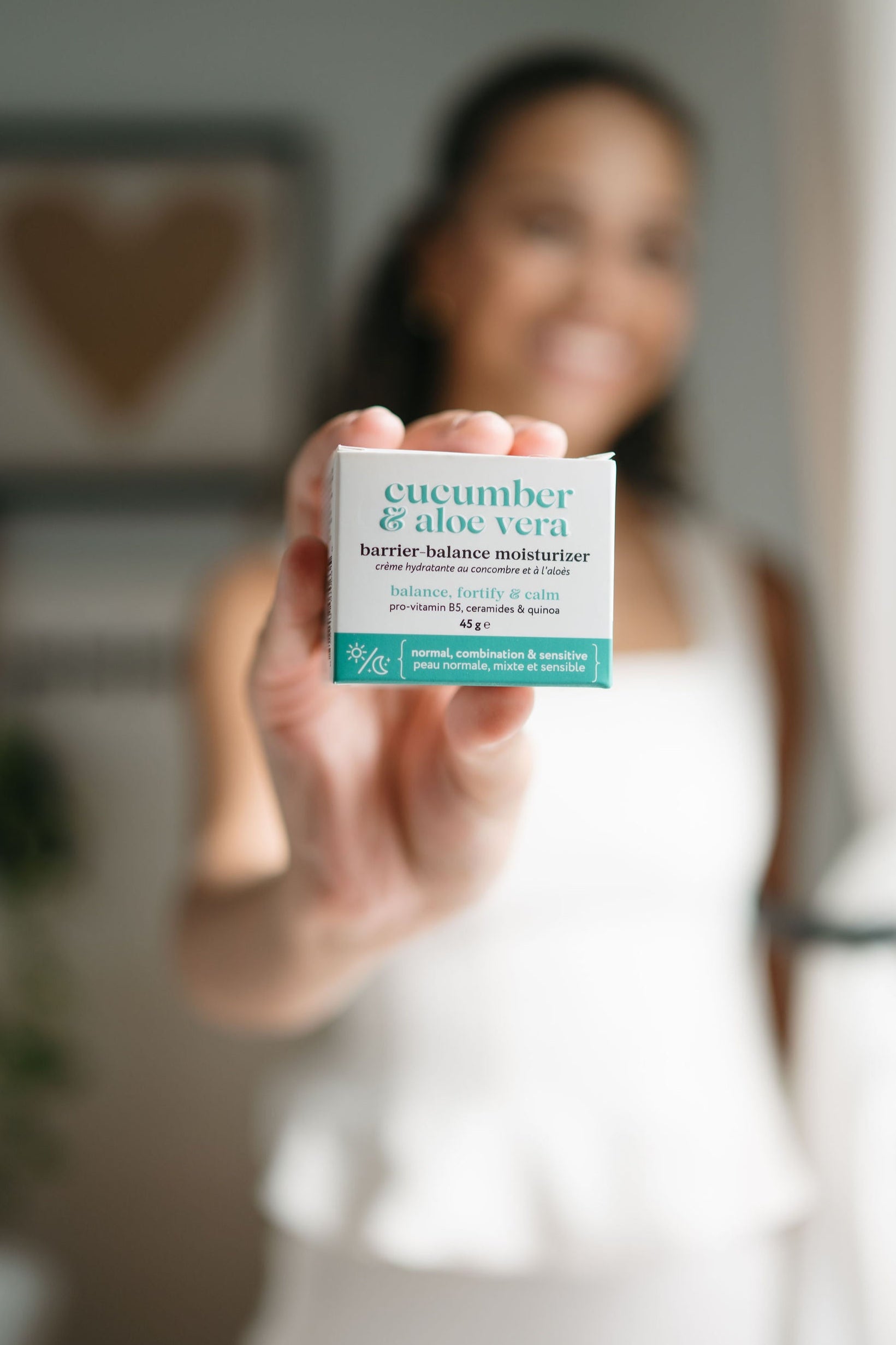 Person holding a skincare product packaging with 'cucumber & aloe vera' text.