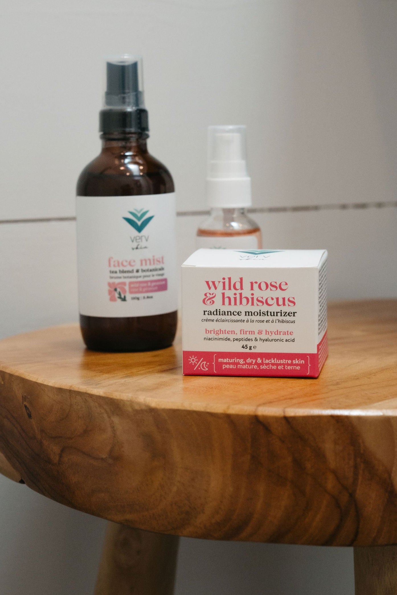 Bottle and box of 'wild rose & hibiscus' product on a wooden stool against a tiled wall.
