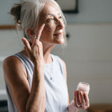 Woman applying cream to her face in a home setting