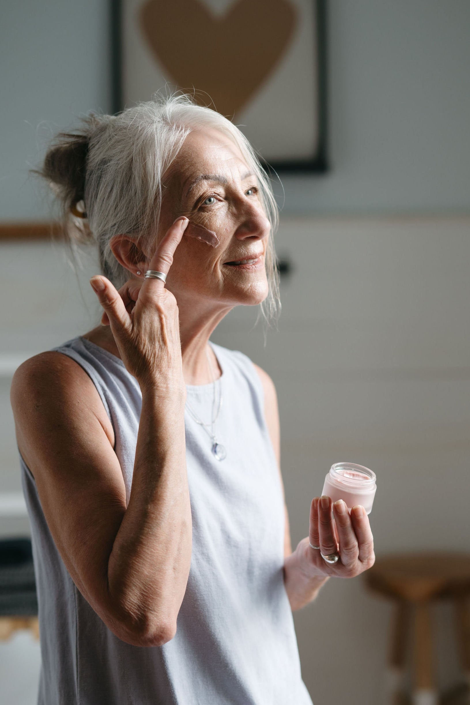 Woman applying cream to her face in a home setting