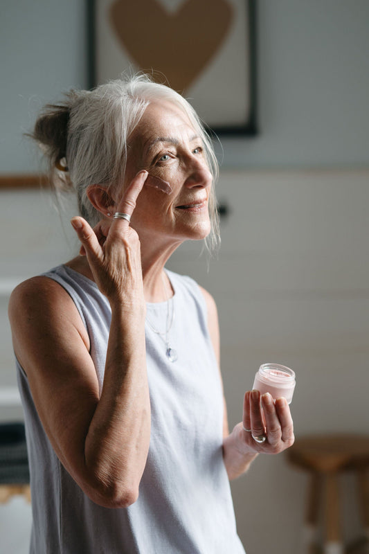 Woman applying cream to her face in a home setting